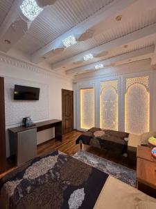 a room with two beds and a tv on the wall at GUZAL Hotel PREMIUM in Bukhara