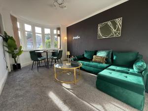 a living room with a green couch and a table at Emerald Manor - Free Parking - Free Wifi in Solihull