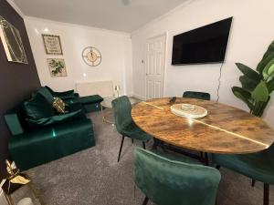 a living room with a wooden table and green chairs at Emerald Manor - Free Parking - Free Wifi in Solihull