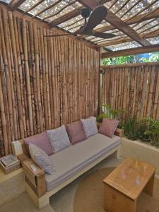 eine Couch auf einer Terrasse mit einer Holzwand in der Unterkunft Lula House in El Nido