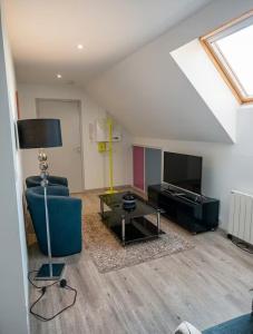 a living room with a couch and a tv at Charmant T2 Cosy - Sous les toits in Luxeuil-les-Bains