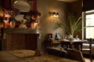 a living room with a fireplace and a table and a mirror at B&B Alexandre in Herzele