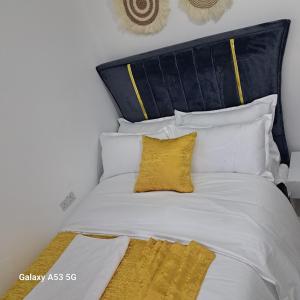a large white bed with a yellow pillow on it at RyNa Homes in Meru +1 photo