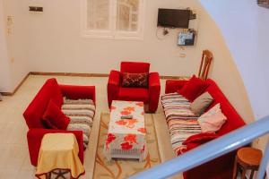 a living room with two red chairs and a couch at Villa Abo Ishak in Luxor