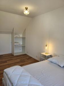 a white bedroom with a bed and a table at petite maison avec jardin in Berck-sur-Mer