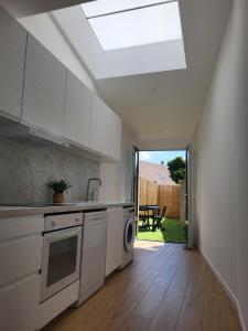 a kitchen with white cabinets and a skylight at petite maison avec jardin in Berck-sur-Mer