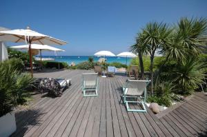 a deck with chairs and umbrellas and the ocean at Sur la plage in Lumio