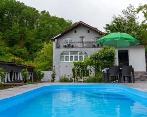 a house with a swimming pool and an umbrella at CasaMarinela in Orşova