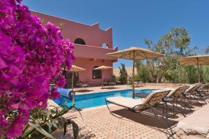 a group of chairs and umbrellas next to a pool at Villa Nouran - Chambre D'Hôte in Ghazoua