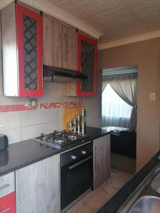 a kitchen with red cabinets and a stove top oven at Imvumbu Guest House in Nelspruit