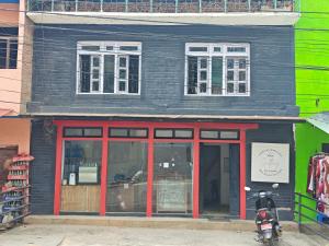 a store with red doors and a motorcycle parked in front at Gatlang Backpackers in Trisūli Bāzār +5 photos