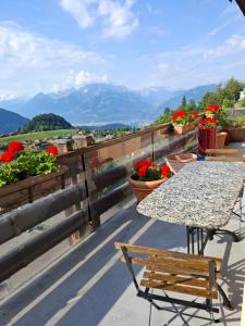 a table and chairs on a balcony with flowers at Le Nid d'aigle apt 405 Leysin centre avec forfait piscine sauna jacuzzi en option in Leysin