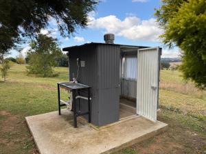 a black outhouse with a table in a field at Tranquility Campsite in Winterton