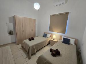 a bedroom with two beds and a cabinet in it at Arzella Beachfront Guesthouse in Birżebbuġa