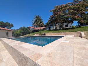 a swimming pool with a stone retaining wall and trees at maison et table d'hôtes Xori Kanta in Ascain
