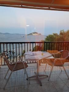 a table and chairs on a balcony with a view of the ocean at attic sea view studio in karmiris studios in Zakynthos
