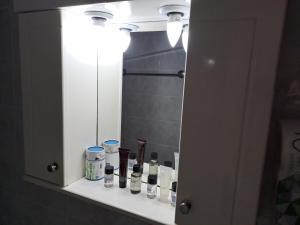a bathroom mirror with a shelf with cosmetics on it at attic sea view studio in karmiris studios in Zakynthos