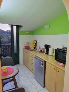 a kitchen with green walls and a table and a counter at attic sea view studio in karmiris studios in Zakynthos