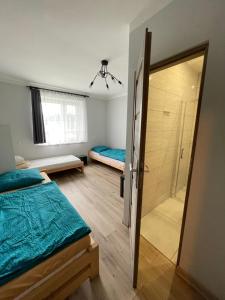 a bedroom with two beds and a shower and a glass door at Na Papierni in Klucze