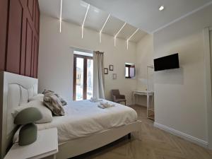 a white bedroom with a bed and a television at La Dimora delle Muse in Sulmona