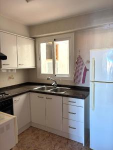 a kitchen with white cabinets and a sink and a refrigerator at Apartamento vacacional Jávea in Jávea