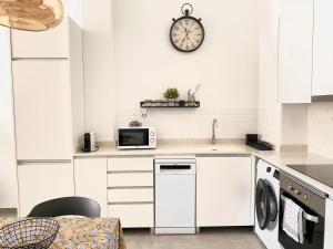 a kitchen with white cabinets and a clock on the wall at Jardín Viveros-Turia in Valencia