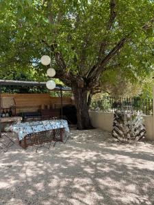 a table and chairs under a tree next to a fence at Mas des garrigues in Bouchet