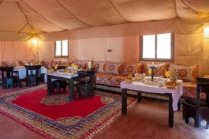 a living room with a couch and tables in a tent at Merzouga Retreat Camp in Merzouga
