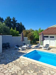 a swimming pool with two chairs and umbrellas at vila lokvanj in Ližnjan