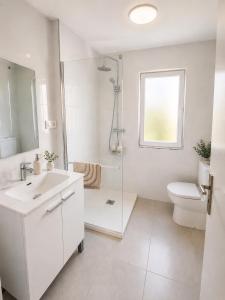a white bathroom with a shower and a toilet at Abuela Maruja - Piso acogedor en Cee, perfecto para desconectar in Cee +19 photos