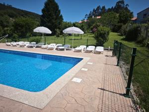 a swimming pool with lounge chairs and umbrellas next to a fence at Casa de Crabera in Dodro
