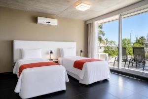 two beds in a room with a large window at Costa Colonia - Riverside Boutique Hotel in Colonia del Sacramento +37 photos