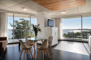 a living room with a table and chairs and a television at Costa Colonia - Riverside Boutique Hotel in Colonia del Sacramento
