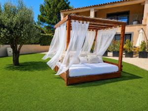 a canopy bed with white pillows on a lawn at Cocon d'Amour & Spa in Le Thoronet