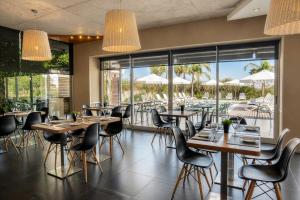a restaurant with tables and chairs and a view of the pool at Costa Colonia - Riverside Boutique Hotel in Colonia del Sacramento