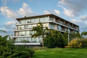 a building with a palm tree in front of it at Costa Colonia - Riverside Boutique Hotel in Colonia del Sacramento