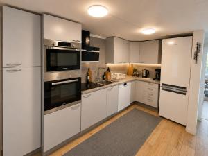 a kitchen with white cabinets and stainless steel appliances at Mysig stuga i Nävesta in Örebro