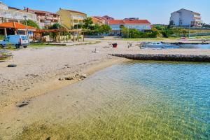 a sandy beach with houses and a body of water at Holiday Home Albina in Kustići