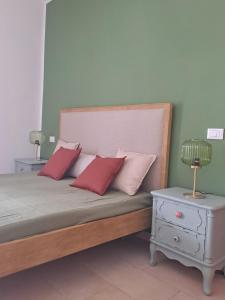 a bed with red pillows and a lamp on a night stand at Chioma verde in Chioma +32 photos