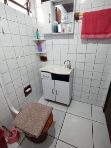a white tiled bathroom with a sink and a toilet at Casa da JEANI CLEIDI in Rosário do Sul