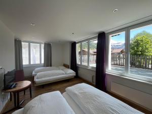 a bedroom with two beds and large windows at Hotel Sternen Budget in Lenk +10 photos
