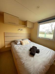 a bedroom with a large white bed with a window at Bungalow Neila in Bourbourg