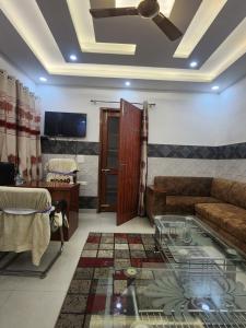 a living room with a couch and a glass table at Private Duplex Stay with Open Terrace in Meerut