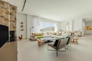 a living room with a couch and chairs and a fireplace at Villa Paschalia,Sea View, Pool, Gym, Sleeps 10 in Mikonos