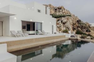 a house with a swimming pool next to a mountain at Villa Paschalia,Sea View, Pool, Gym, Sleeps 10 in Mikonos