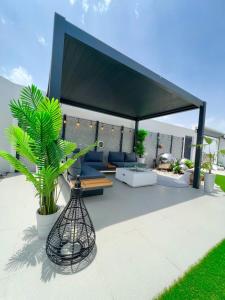 a patio with a black cover with a bench and a plant at Rosella Chalet in Jabal Al Akhdar +17 photos