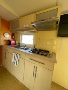 a small kitchen with a stove and a sink at Chloe Bungalow in Bourbourg