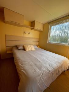 a bedroom with a large white bed with a window at Chloe Bungalow in Bourbourg
