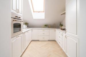 a white kitchen with white cabinets and a skylight at Apartament nad bulwarem in Lidzbark Warmiński