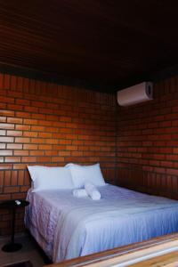 a bed in a brick room with two white pillows at Oliveira mountain House in Tijucas